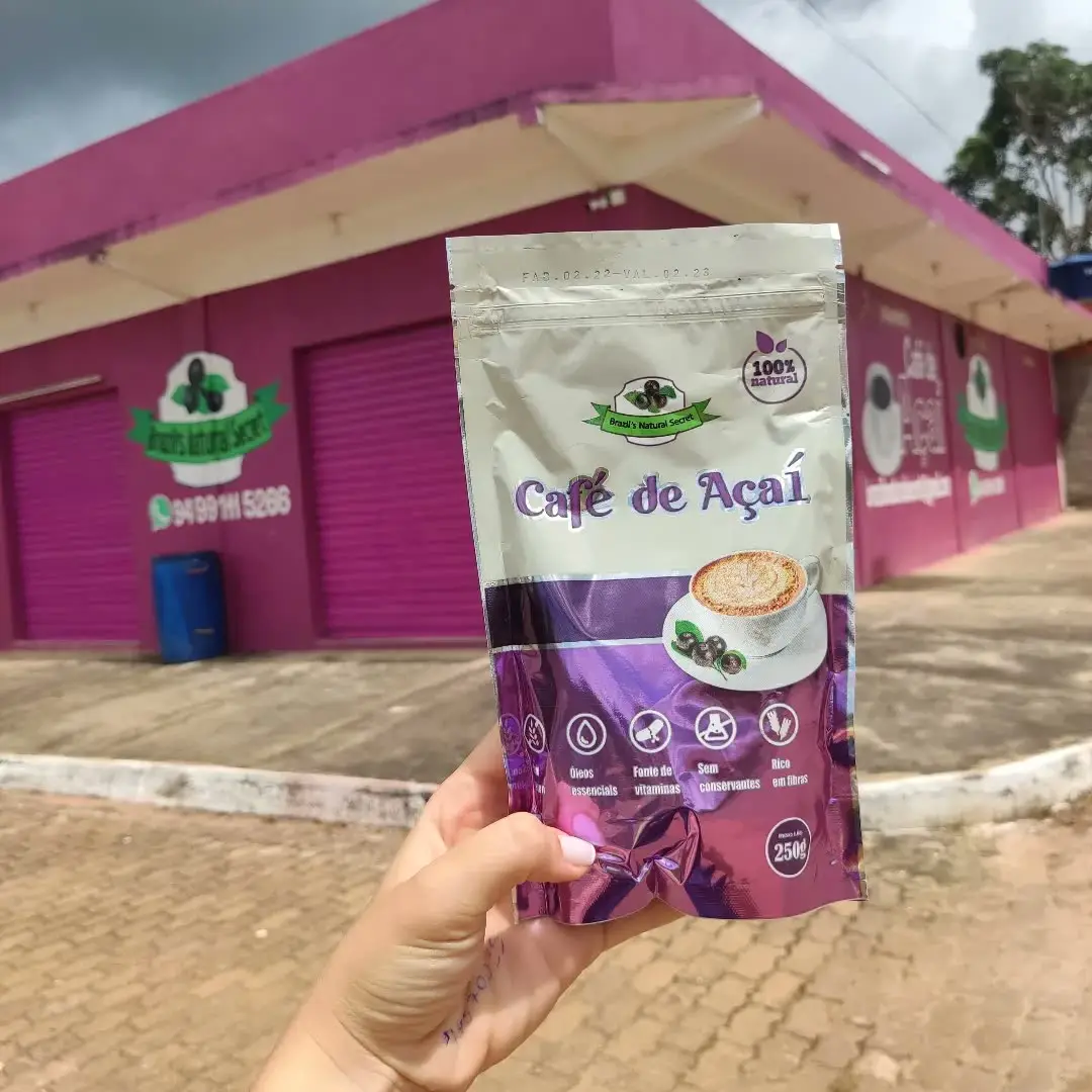 A pouch of Dripssai held up in front of the magenta-painted factory in Itupiranga.